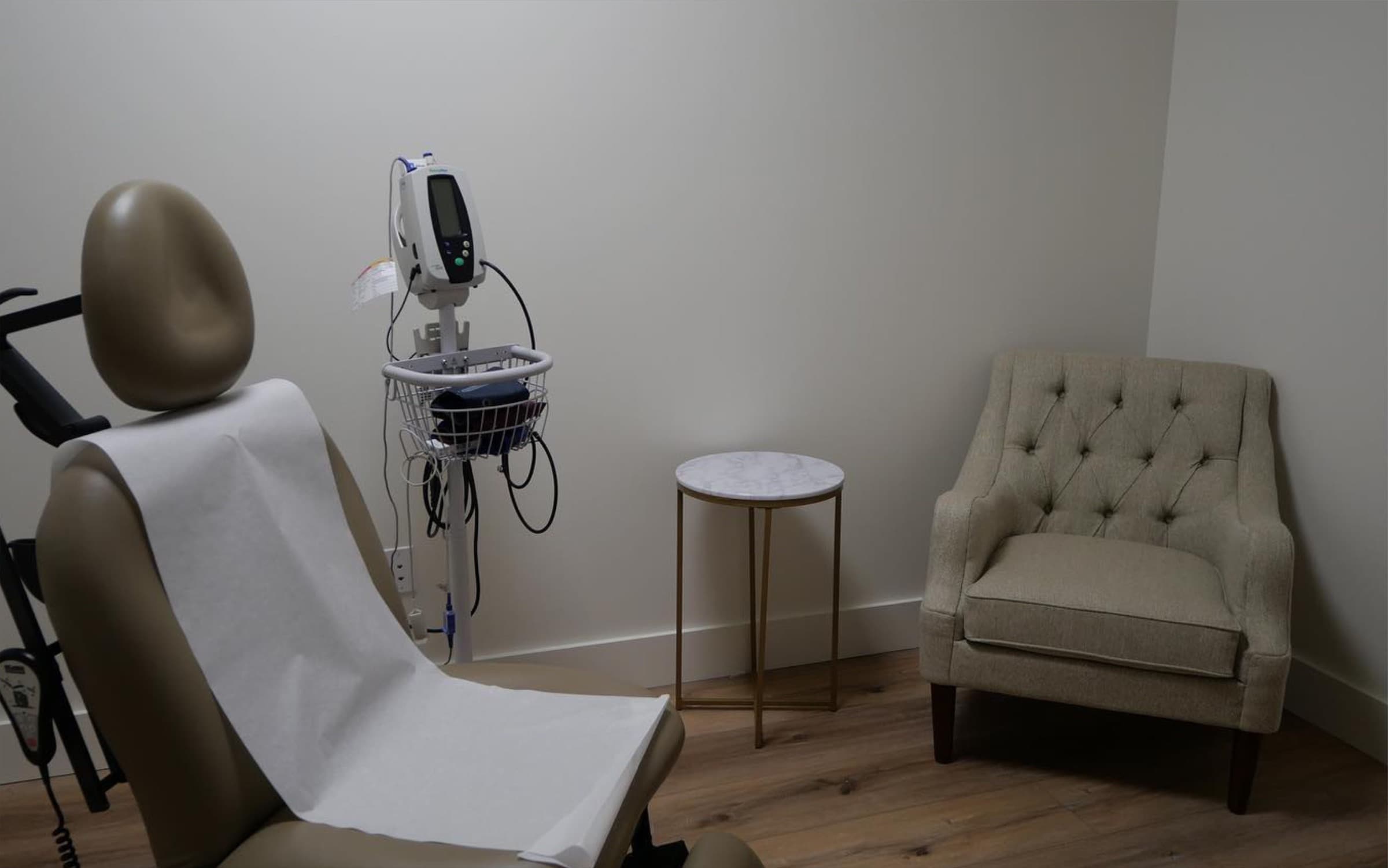 Exam room with a patient chair, medical monitor, and guest chair