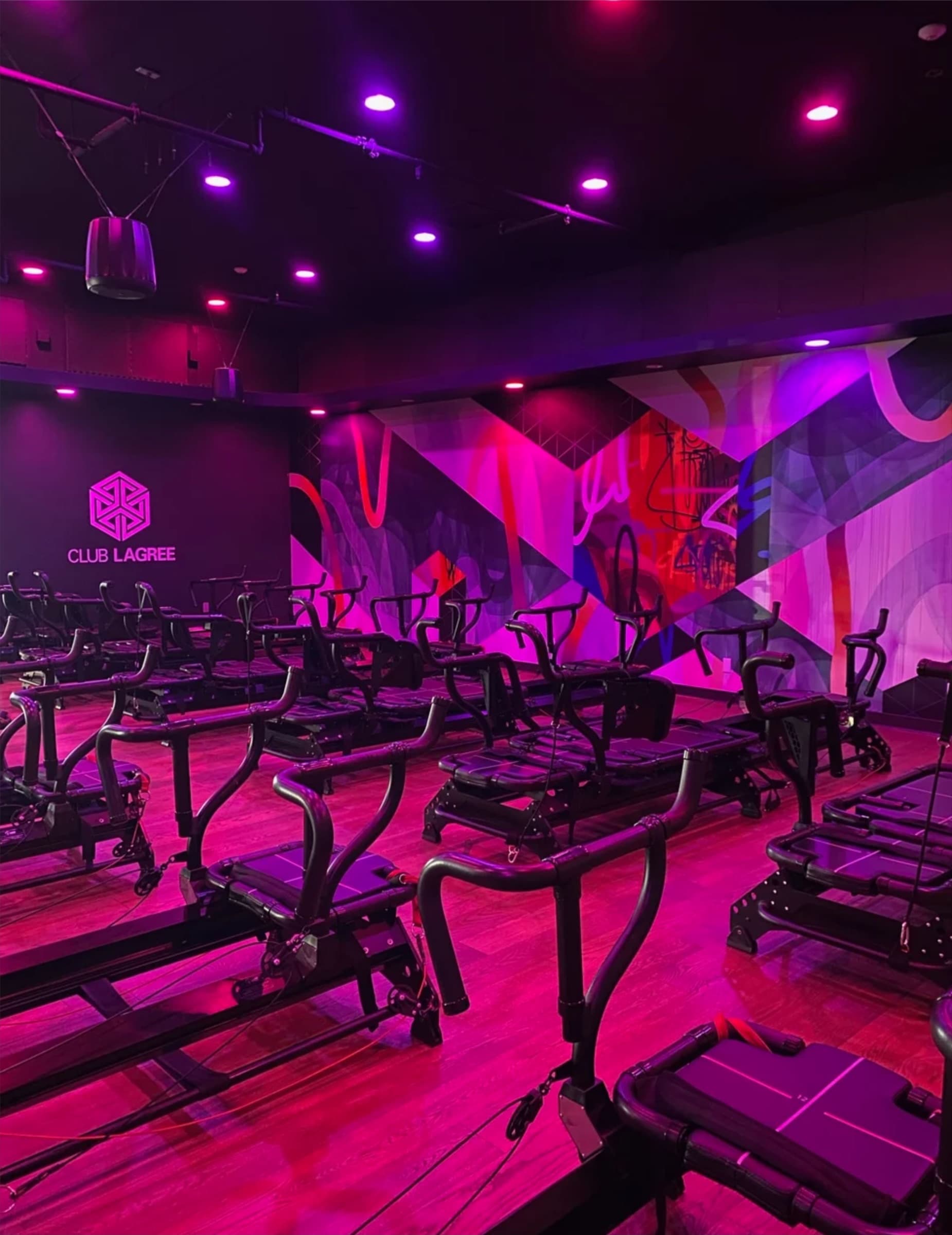 Club Lagree studio with exercise machines and a wall mural