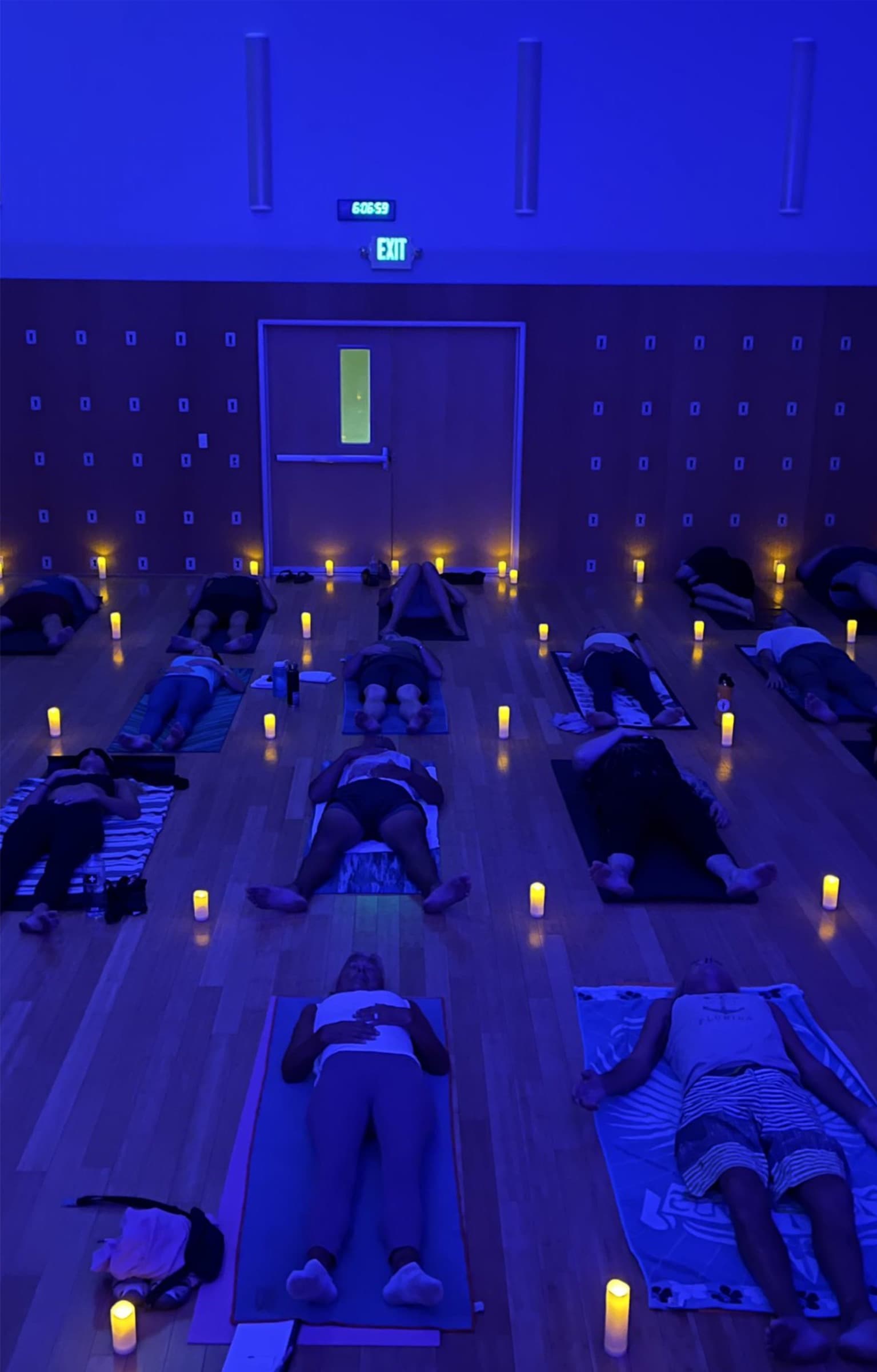 People lying on yoga mats in a blue-lit Westlake Yoga Co. studio